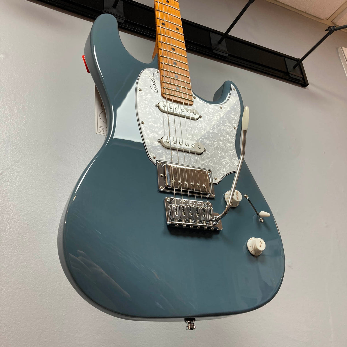A Godin Session T-Pro with Bag electric guitar in blue, featuring an H-S-S pickup setup, pearloid pickguard, and whammy bar, by Godin, photographed from below against a light gray wall.