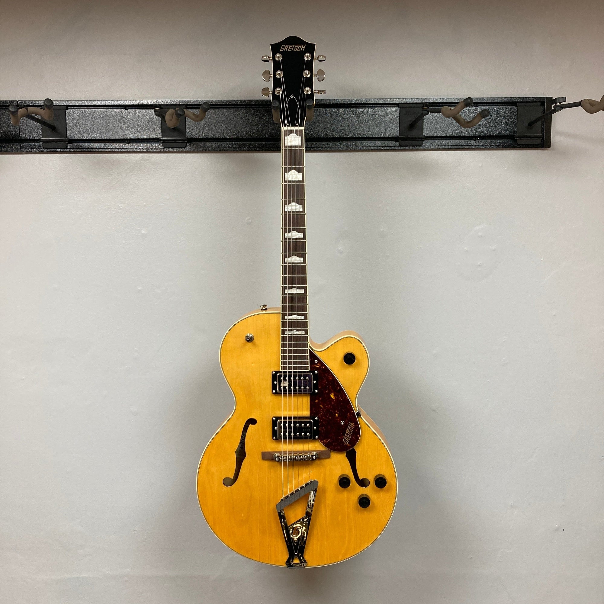 Gretsch G2420 Streamliner Village Amber guitar displayed on wall, highlighting its strings and body design. Ideal for enthusiasts seeking quality sound and craftsmanship.