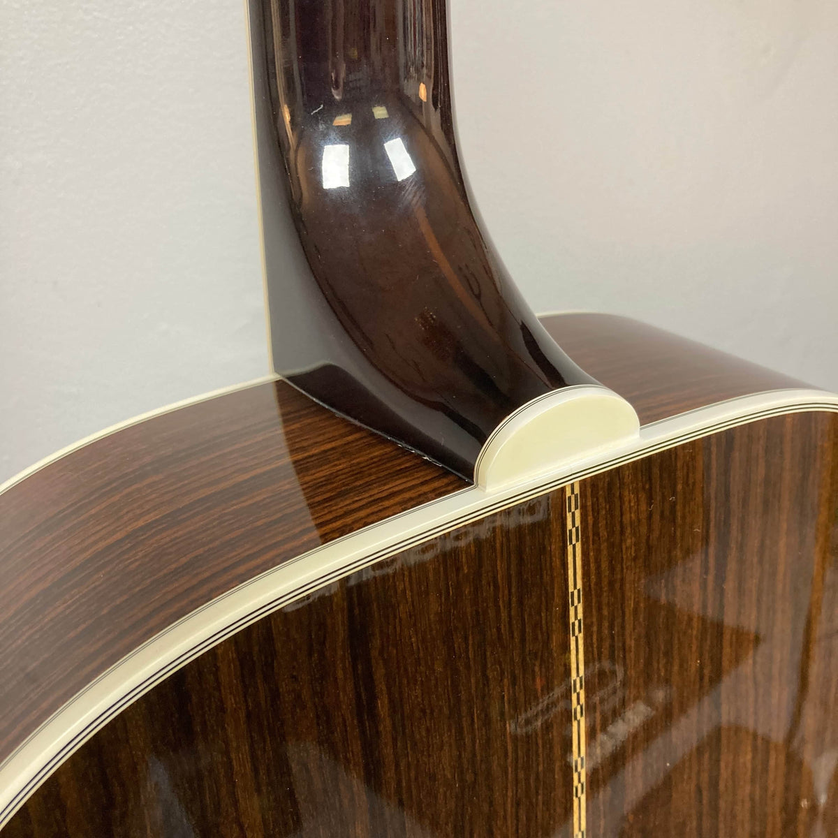 Close-up of the neck joint and back of a Guild USA F-512 w/OHSC 2005 Circa jumbo 12-string by Guild, highlighting its glossy finish, cream binding, and decorative back strip.