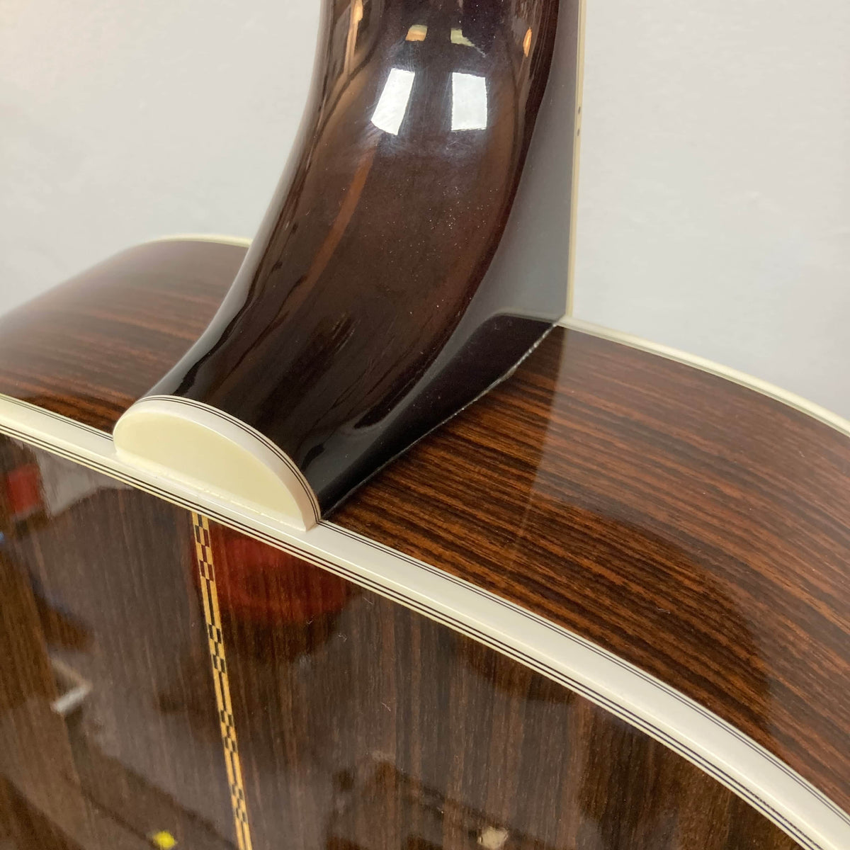Close-up of the neck joint and back of a Guild USA F-512 w/OHSC 2005 Circa jumbo 12-string, highlighting its dark wood grain, cream binding, and exquisite craftsmanship.
