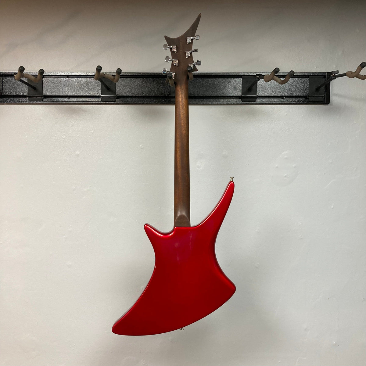 Guild USA X-79 Candy Apple Red electric guitar with an avant-garde body shape, 24-fret fingerboard, and brown handle, displayed on a wall.