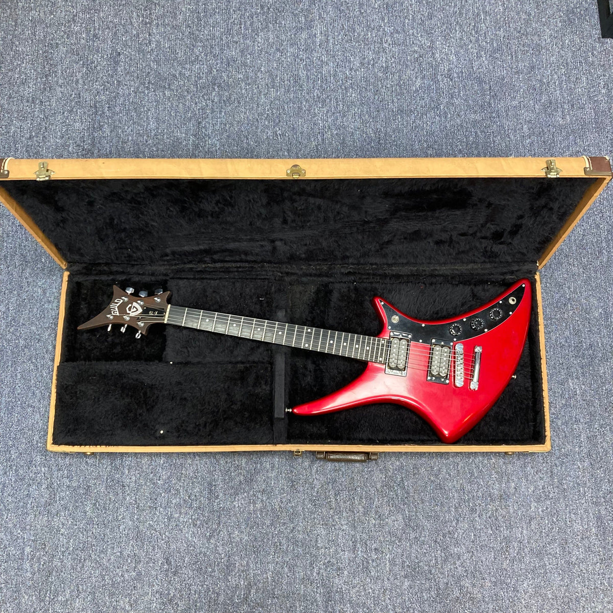 Guild USA X-79 Candy Apple Red electric guitar in case, featuring a 24-fret fingerboard and avant-garde body shape from the 1980s.