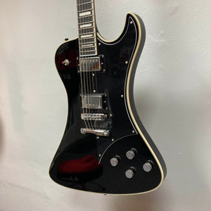 The Hagstrom Fantomen Custom Black w/case electric guitar by Hagstrom features a glossy black finish, cream binding, chrome hardware, a pair of Lundgren Design humbuckers, four control knobs, and a three-way pickup selector switch. It is displayed hanging against a white wall.