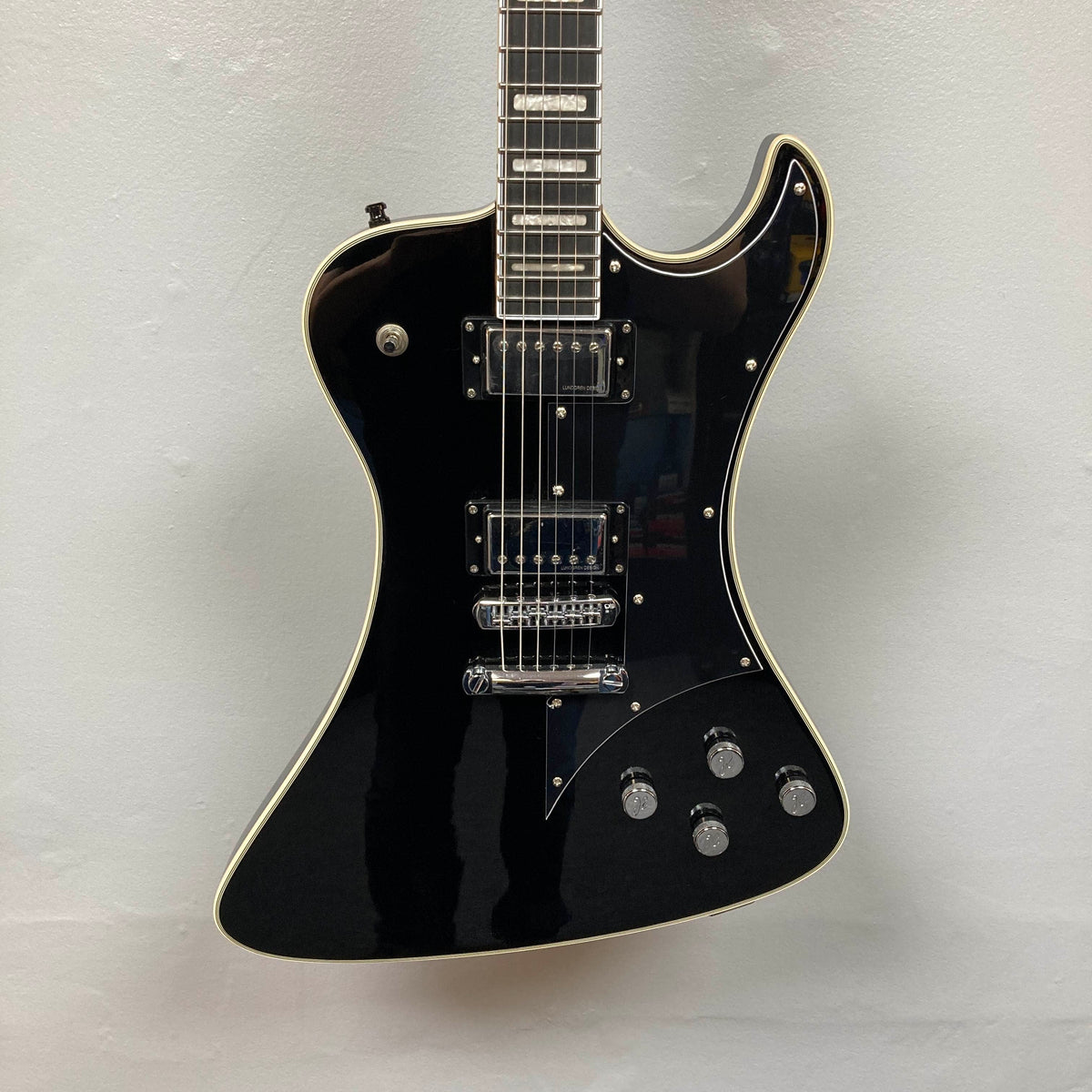 The Hagstrom Fantomen Custom Black w/case electric guitar by Hagstrom, featuring a distinctive offset body shape, chrome hardware, two Lundgren Design humbucker pickups, four control knobs, and white binding, is photographed against a plain white background.