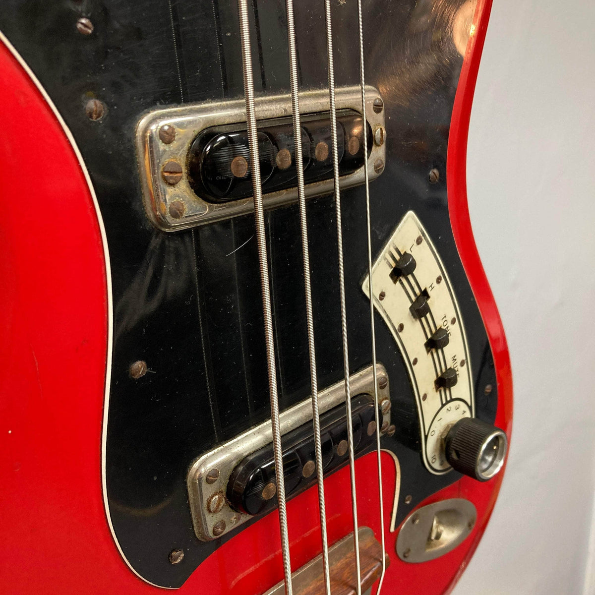 Hagstrom HII-B mid-1960s red bass guitar, showcasing metal-covered pickups, black pickguard, and control panel with sliders, highlighting vintage Scandinavian design and craftsmanship.