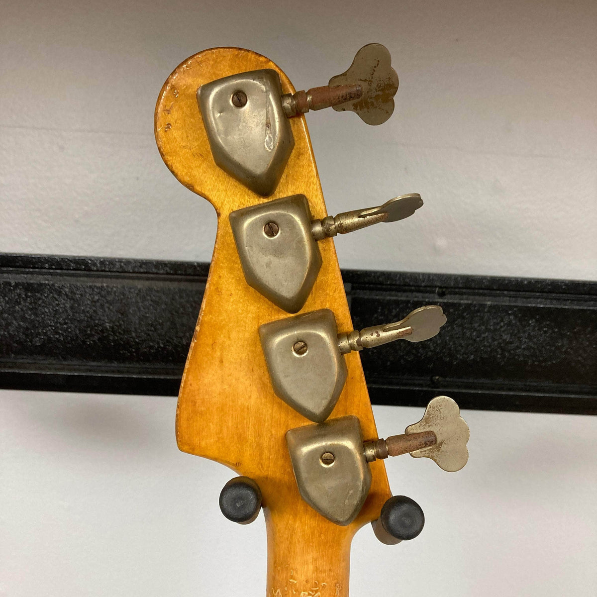 Hagstrom HII-B Mid-1960s Red Medium-Scale Bass headstock close-up, showcasing original metal tuning machines on a light wooden surface, emphasizing vintage craftsmanship.