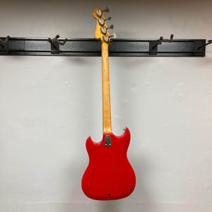 Hagstrom HII-B Mid-1960s Red Medium-Scale Bass, serial 643772, hanging on a wall rack, showcasing its double-cutaway design and maple neck with four tuning pegs.