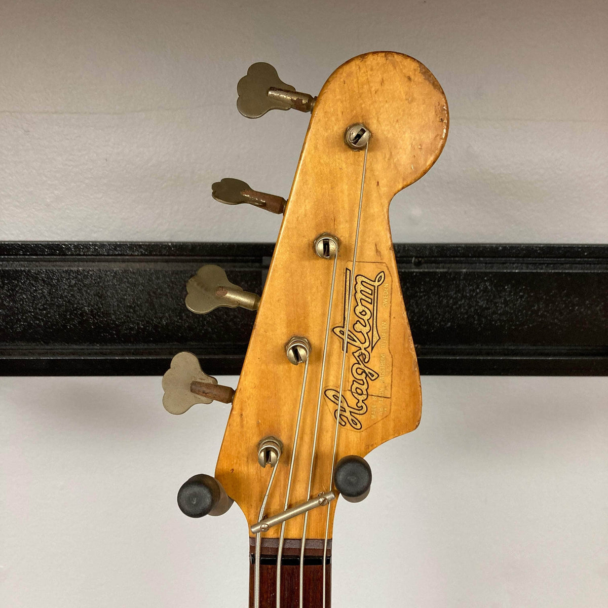Hagstrom HII-B Mid-1960s Red Bass headstock, featuring logo, four tuning pegs, and strings; a vintage instrument known for its unique tone and Scandinavian design.