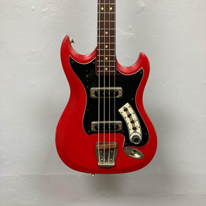 Hagstrom HII-B Mid-1960s Red Medium-Scale Bass, features dual pickups, distinctive design, vintage character, hanging against a light-gray wall.