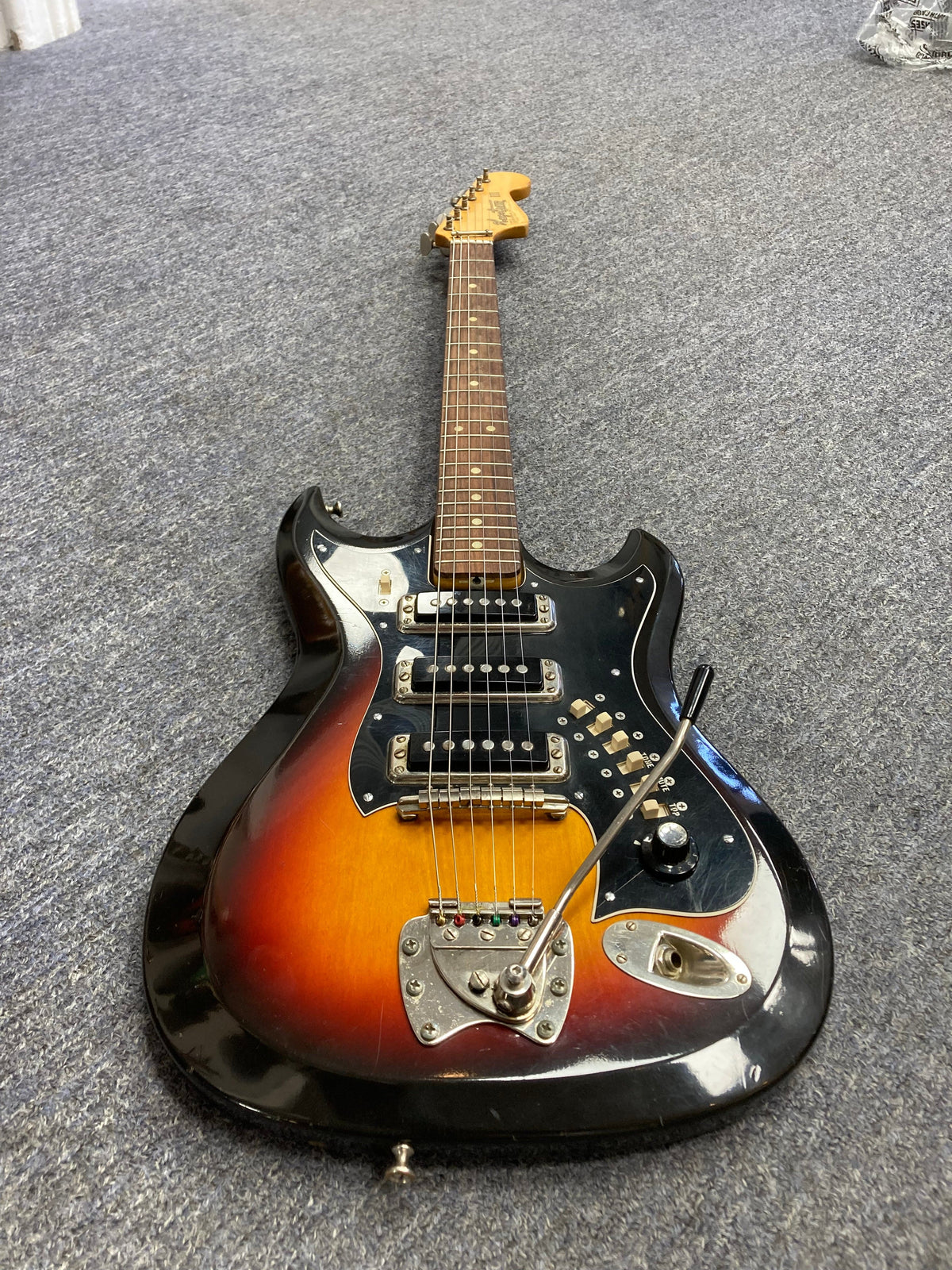 Hagstrom III 1960s Sunburst electric guitar on the floor with original case, showcasing vintage quality and minor wear. Available at Guitars on Main.