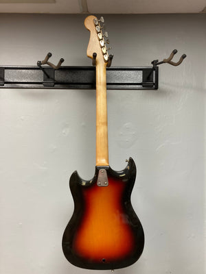 Hagstrom III 1960s Sunburst electric guitar mounted on a wall, showcasing vintage craftsmanship, with visible minor scratches indicating its rich history. Original case included.