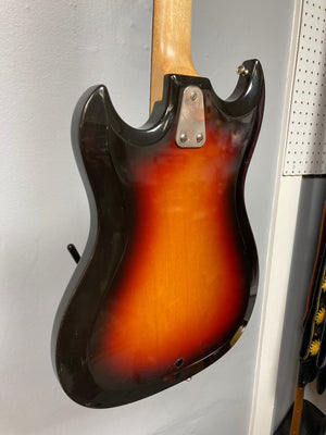 Hagstrom III 1960s Sunburst Electric Guitar hanging on a wall, showcasing its vintage craftsmanship and classic design. Original case included.