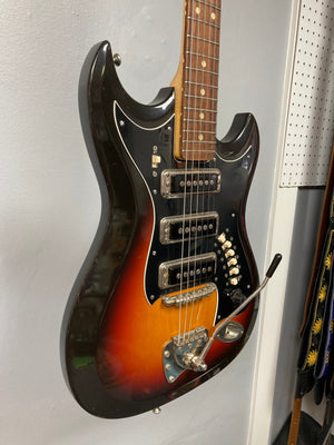 Hagstrom III 1960s Sunburst Electric Guitar with original case, showcasing vintage craftsmanship and minor wear, mounted on a wall.