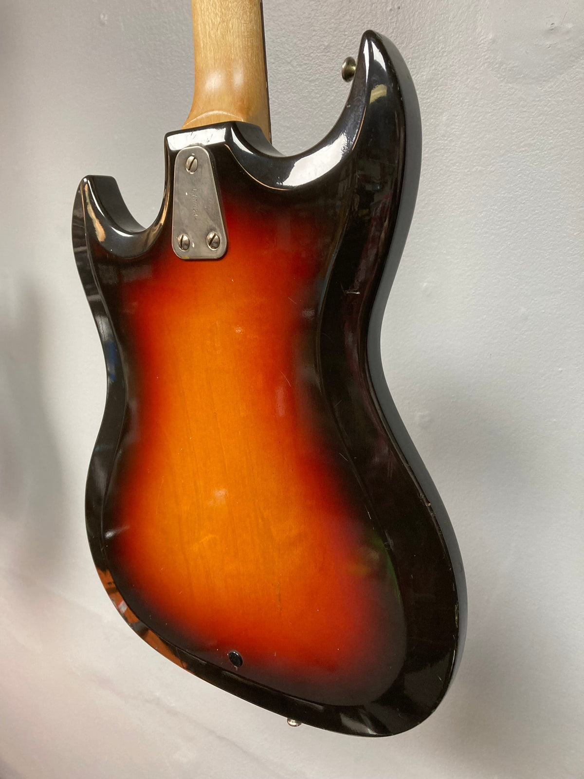 Close-up of a vintage 1960s Sunburst Hagstrom III electric guitar, showcasing its craftsmanship and original case.