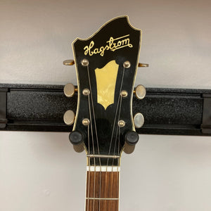 Hagstrom Viking 1968 Natural w/Case: Vintage guitar on wall displaying unique body shape and detailed craftsmanship, ideal for collectors and musicians.