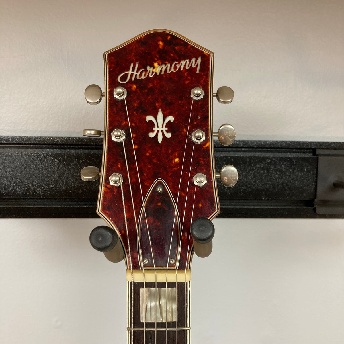 Harmony H-75 1960s Sunburst guitar on a stand, showcasing its classic design with visible minor finish blemishes on the body.