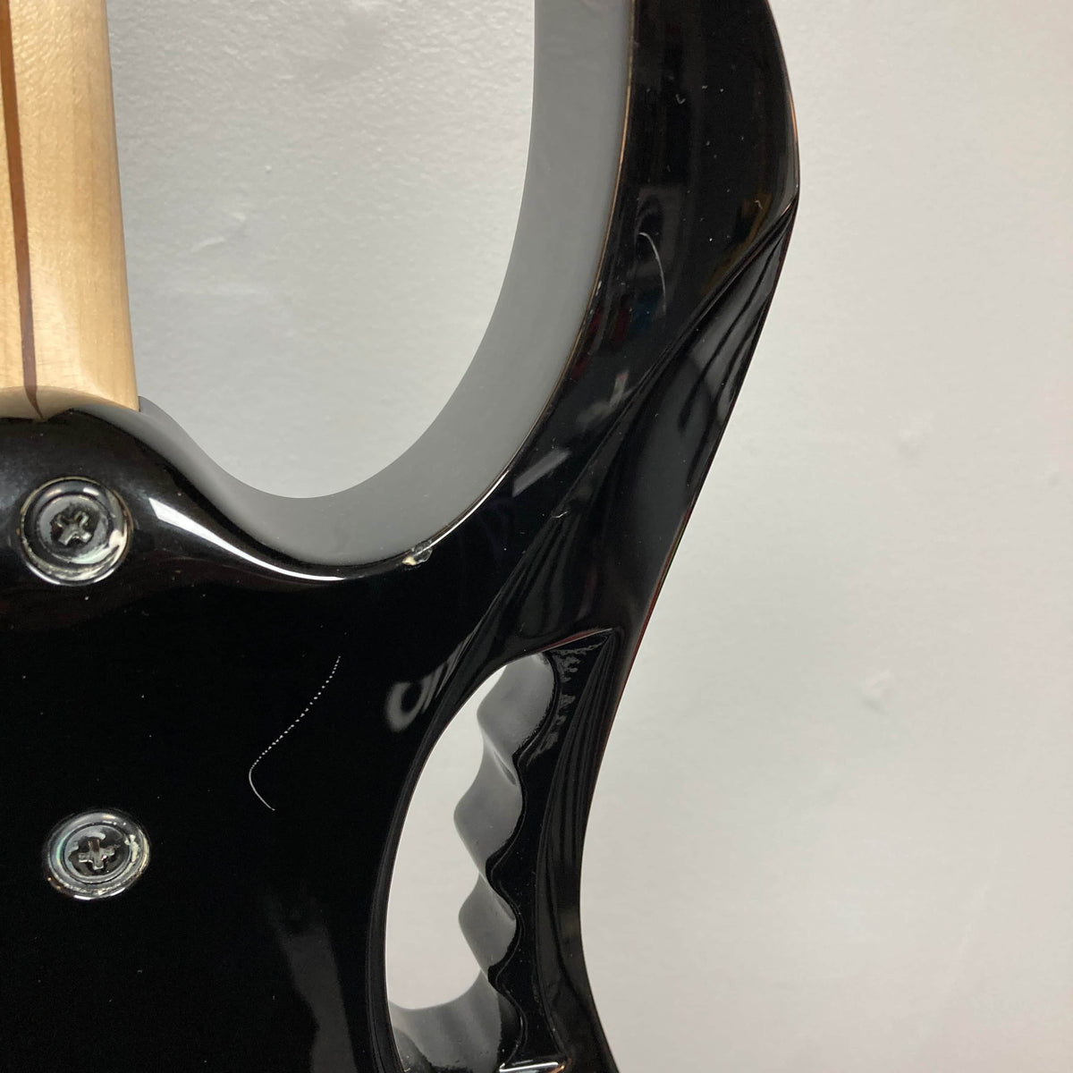 Close-up of the back of a black Ibanez JEM77P Steve Vai Signature electric guitar from Guitars on Main, highlighting the neck joint, screws, and contoured cutouts against a plain white background.