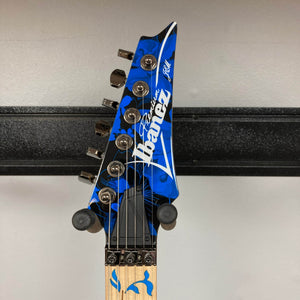 Close-up of the Ibanez JEM77P Steve Vai Signature electric guitar headstock, featuring a blue design, six tuning pegs, and locking nut hardware. Available at Guitars on Main.