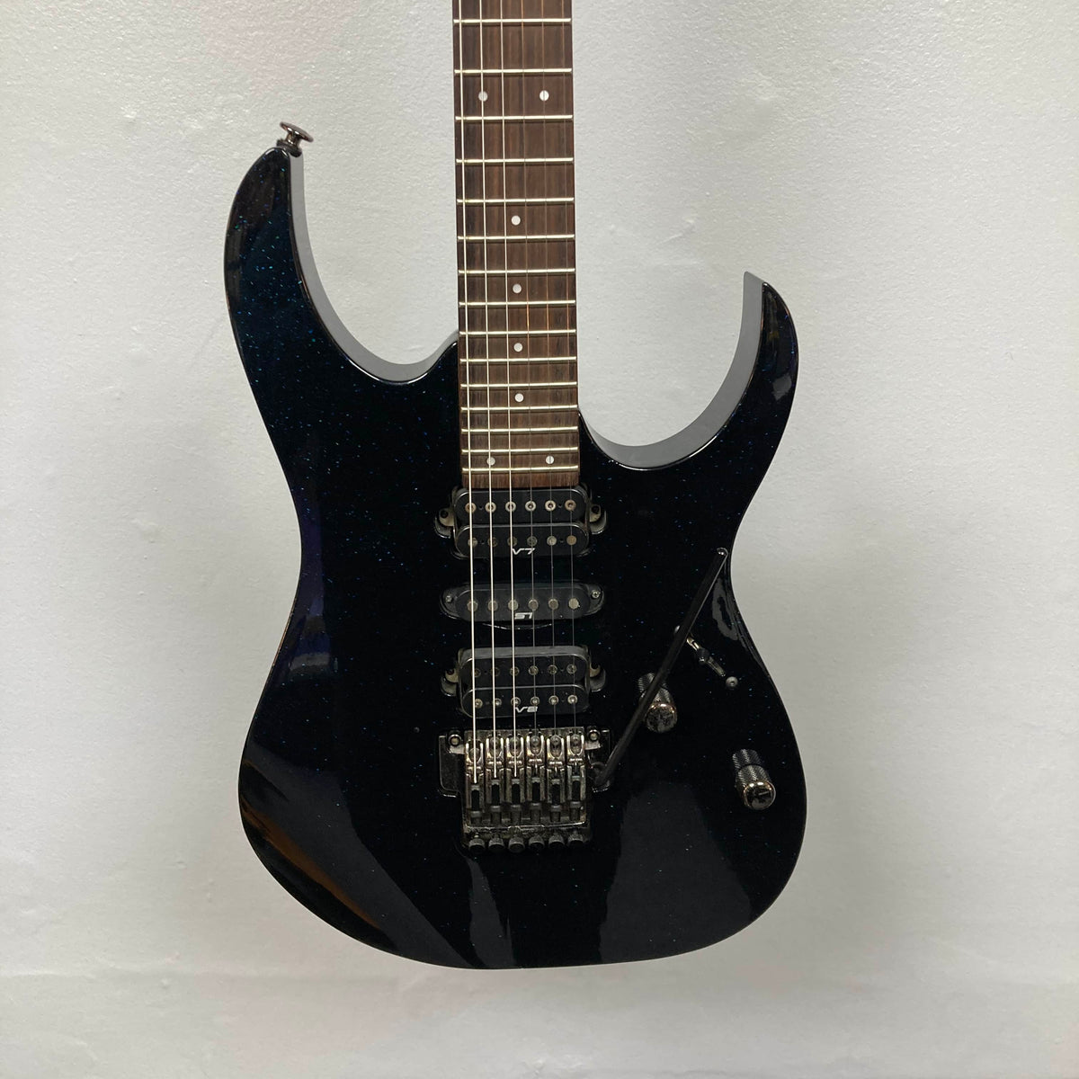 An Ibanez Prestige RG1570 electric guitar in Cosmic Blue with a double cutaway body, three pickups, Wizard Prestige neck, tremolo bridge, and control knobs is shown with its case against a plain white background.