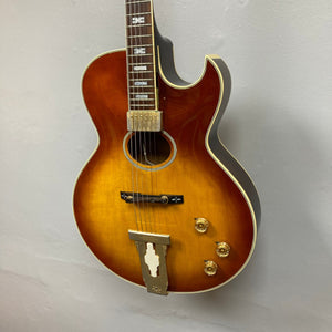 Ibanez Starfield hollow body guitar with case, showcasing a vintage-inspired design and glossy finish, mounted on a white wall.