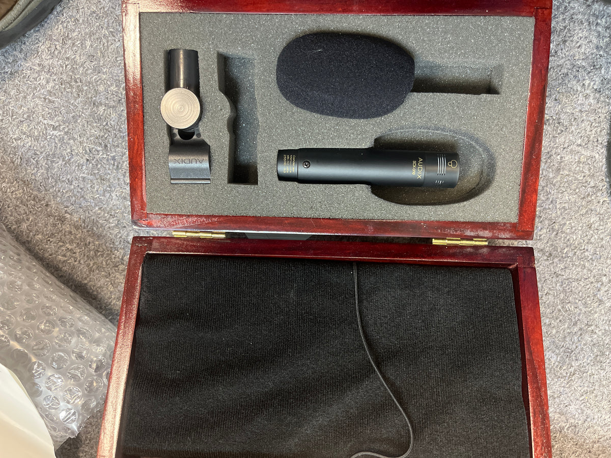 A foam-lined wooden case with a black cloth bottom includes a preowned Audix SCX1-hc Professional Hypercardioid Condenser Microphone, foam windscreen, and mic clip.