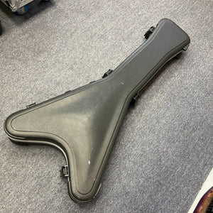 A black, V-shaped Jackson hard guitar case with clasps—designed to fit the signature Phil Demmel Demmelition King V—is shown closed on a gray carpeted floor.