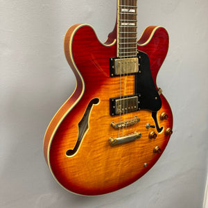 Johnson JH-250-C Semi Hollow Cherry Burst guitar displayed on a wall, showcasing its detailed strings and craftsmanship.