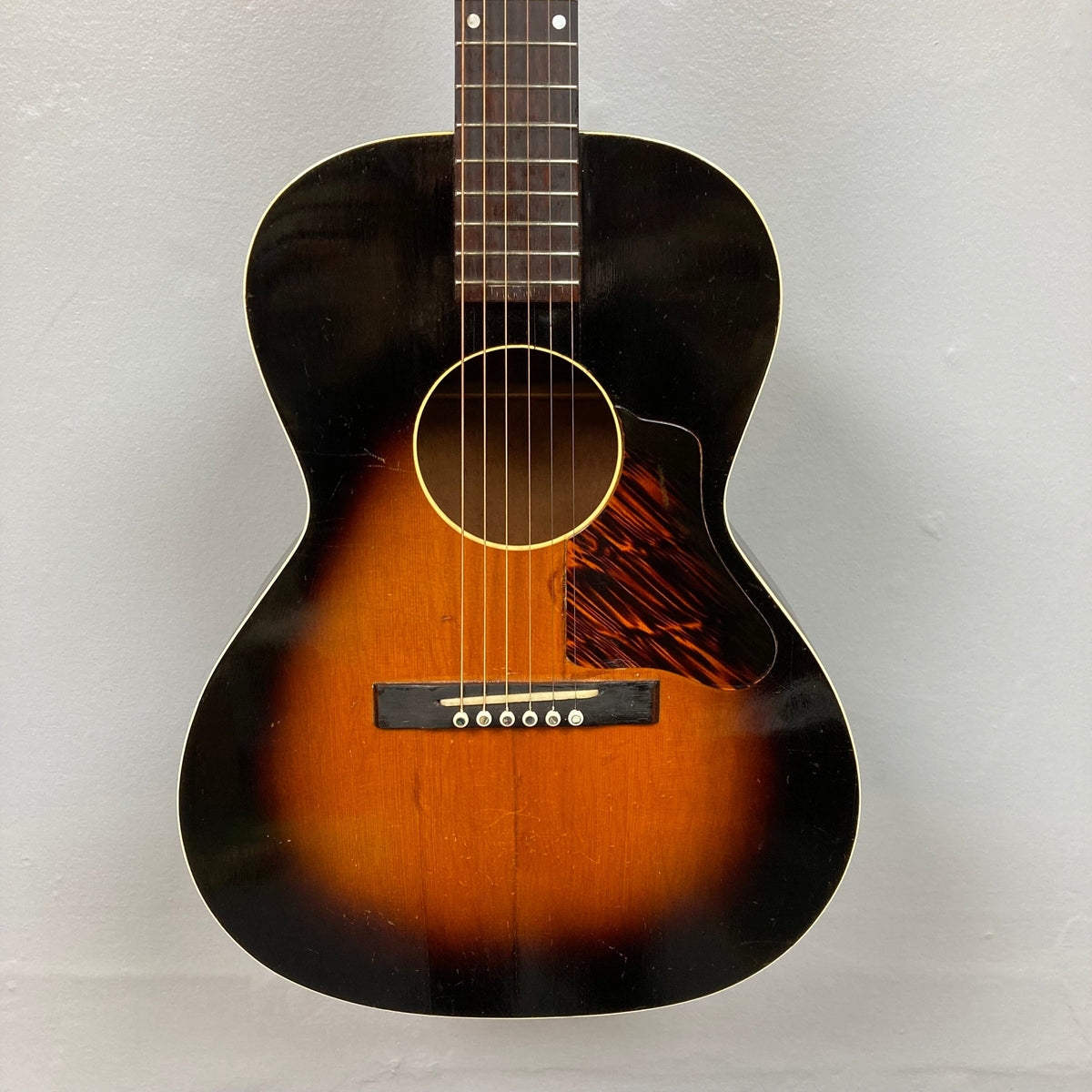 Kalamazoo KG-14 1930s-1940s Sunburst guitar with restored neck joint and bridge, showcasing vintage craftsmanship and enhanced playability, displayed on a wall.