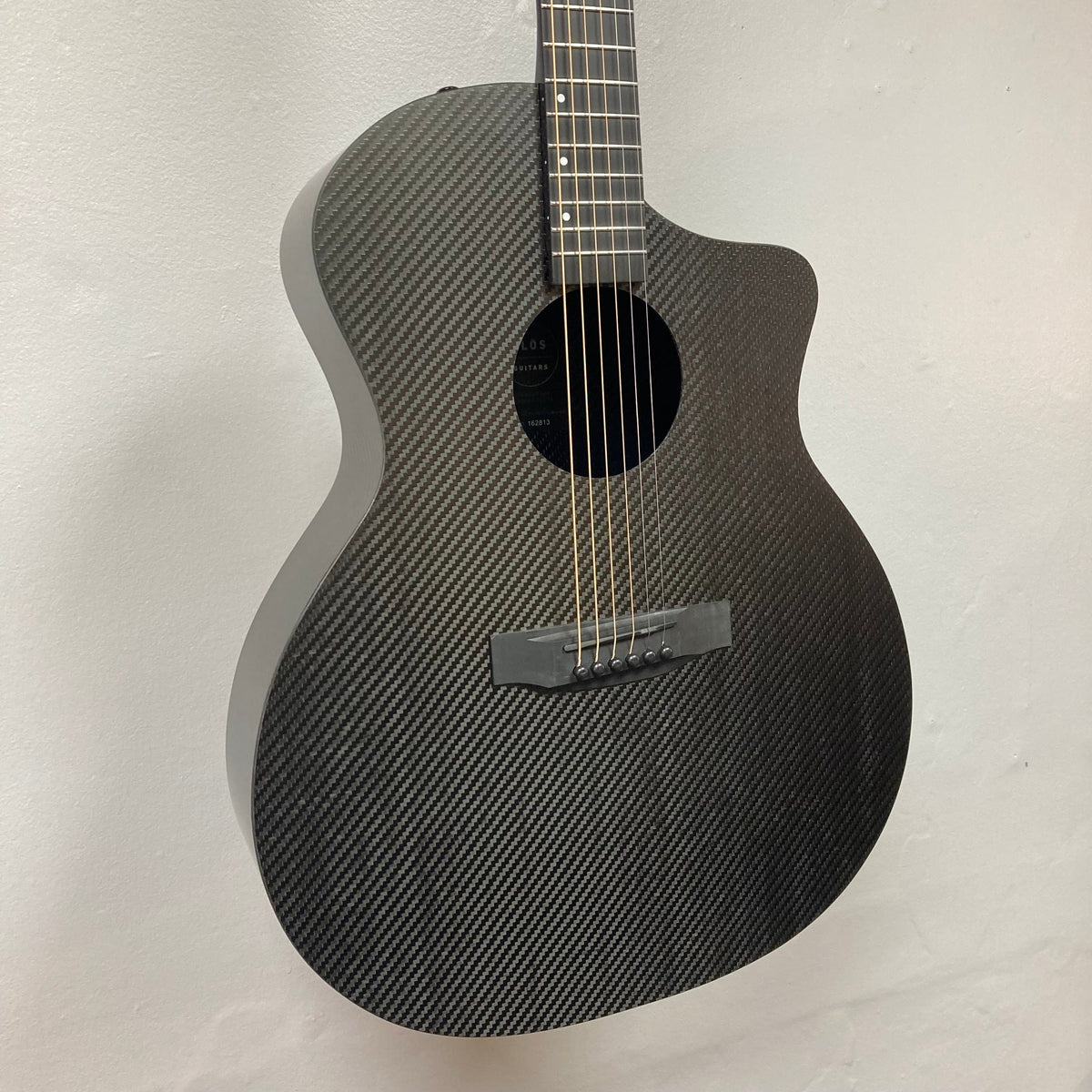 KLOS Grand Cutaway Acoustic Guitar with Fishman Sonitone Piezo, featuring a carbon fiber body, displayed against a white wall.