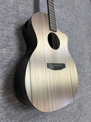 A Klos Grand Cutaway AE w/Fishman acoustic guitar with a striped, light-colored wood finish rests on a gray carpeted surface.