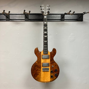 Kramer 650G Deluxe 1986 guitar with case, hanging on a wall, showcasing its vintage design and craftsmanship.