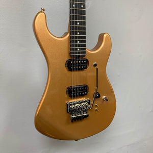 A Kramer 84 HH Killswitch electric guitar in Smoked Almond Metallic with dual humbuckers, Floyd Rose tremolo, and black knobs hangs against a plain light wall. Includes gigbag.