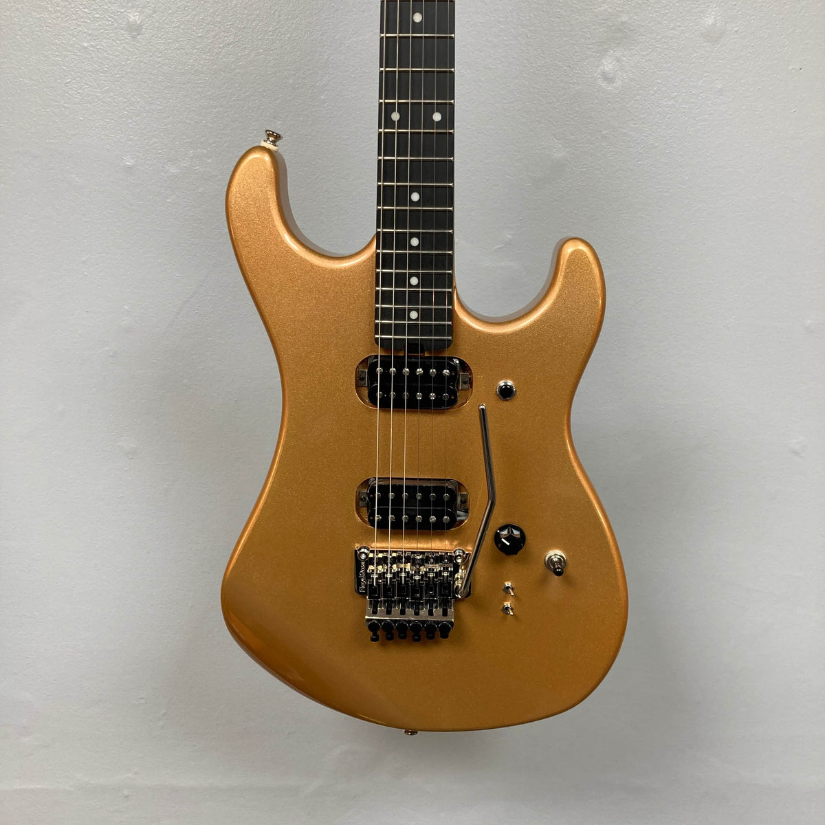 A Kramer 84 HH Killswitch electric guitar in Smoked Almond Metallic with dual humbuckers, black Floyd Rose tremolo, and black knobs, by Kramer, shown against a plain light gray wall. Comes with gigbag.