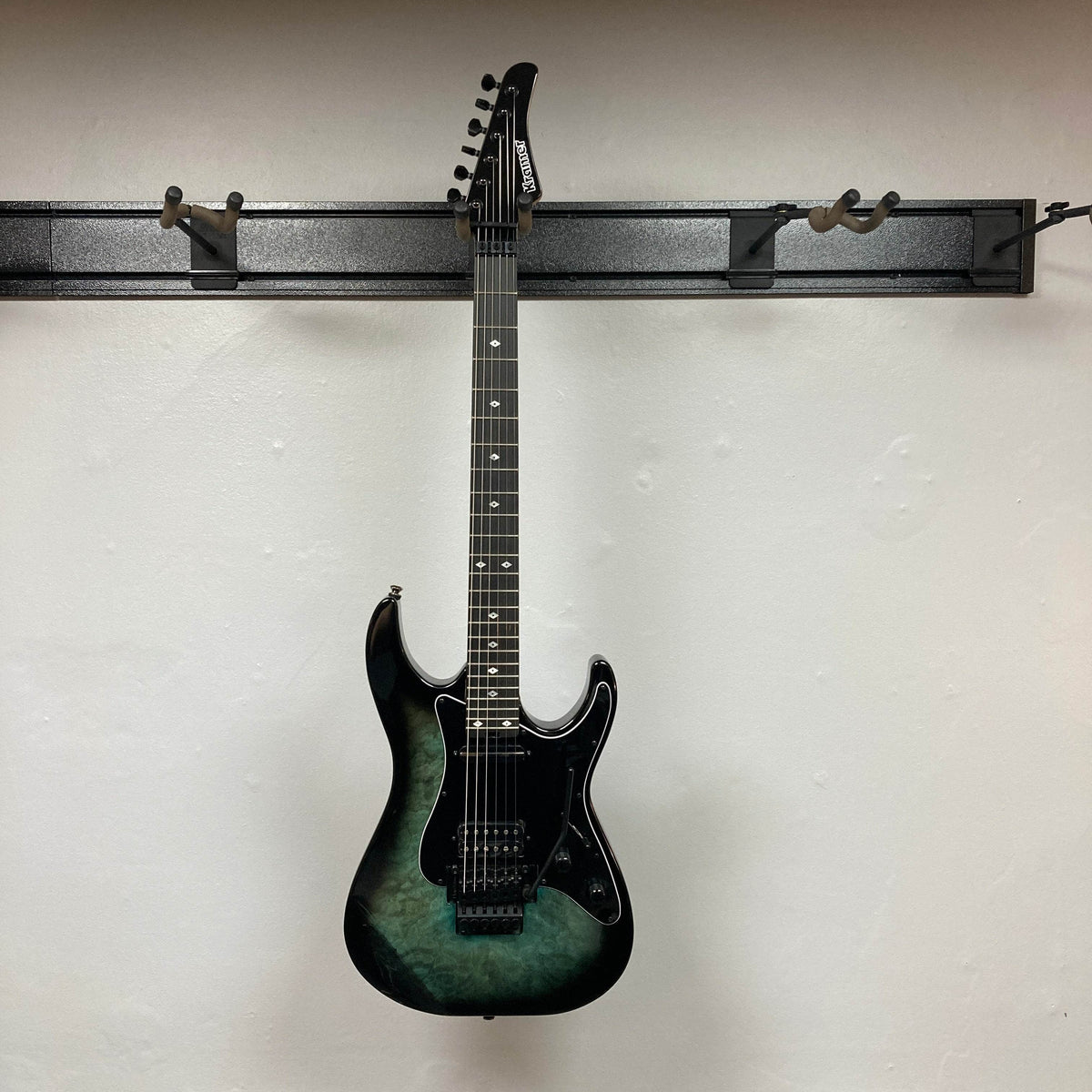  electric guitar hanging on a wall mount against a grey background