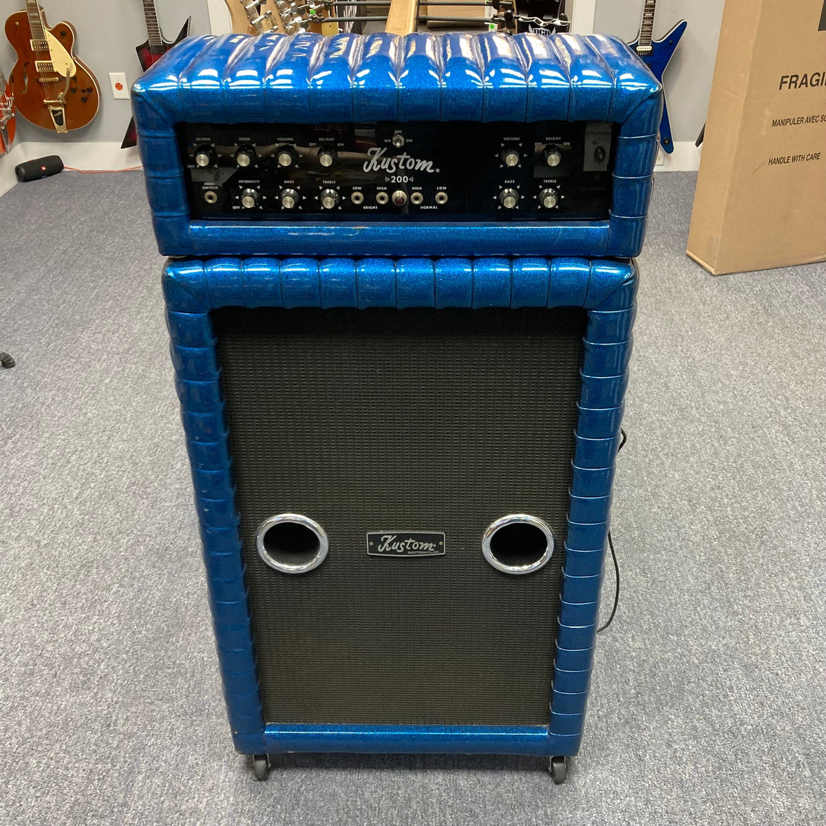 Kustom K200-B2 Blue Head and Cabinet Amp with knobs and buttons for versatile tone shaping, displayed in a music setting.