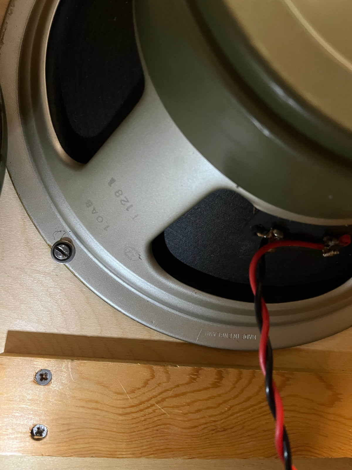 Close-up of a mounted speaker inside a wooden enclosure resembling the 1969 Marshall 4x12 Cabinet with matching Celestion T1281 Greenbacks, highlighting the classic cone, wiring, and mounting screws.
