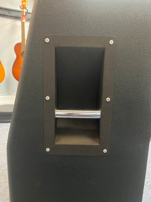 Close-up of the built-in metal handle on a black 1969 Marshall 4x12 Cabinet with Matching Celestion T1281 Greenbacks; blurred guitars appear in the background.