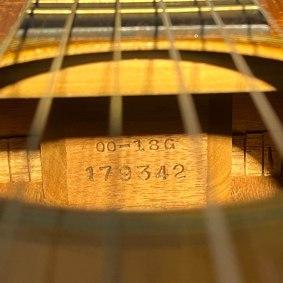 Close-up of the interior of a Martin 00-18G Classical Guitar, c. 1961–1962, showing the model and serial numbers stamped on the wood inside this nylon string instrument.