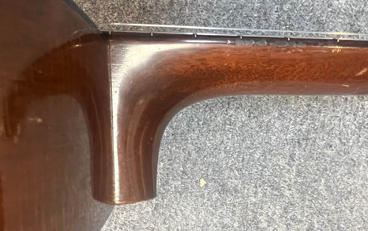 Close-up of the neck joint on a Martin 00-18G Classical Guitar, c. 1961–1962, with nylon strings by Martin, resting on a textured gray carpet.