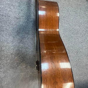 Side view of a Martin 00-18G Classical Guitar, c. 1961–1962, with nylon strings and a wooden body by Martin, resting on a gray carpeted floor.