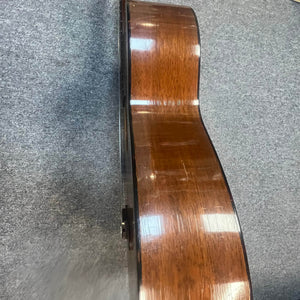 Side view of a Martin 00-18G Classical Guitar (c. 1961–1962) with nylon strings and a glossy wooden finish, lying on a gray carpeted floor.