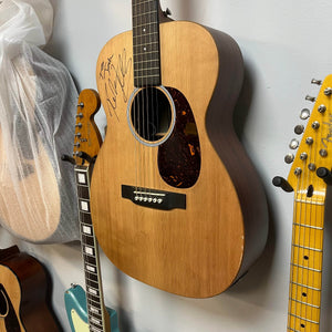 Martin 00X1AE Acoustic-Electric Guitar | Signed by Ex-Poison Guitarist Richie Kotzen hanging on a wall, featuring the autograph on the body above the soundhole.