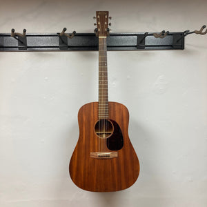 Martin D-15M acoustic guitar hanging on a wall hook, showcasing its solid mahogany construction and classic dreadnought shape.