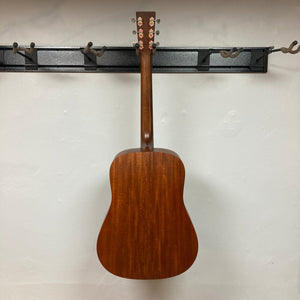 Martin D-15M acoustic guitar on a wall, showcasing its solid mahogany construction and dreadnought shape, highlighting its craftsmanship and vintage aesthetics.