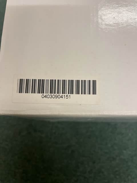 A white box with a barcode sticker showing 04030904151, possibly containing a Monster Power AVS 2000 PRO Professional Reference Automatic Voltage Stabilizer by Monster Power, rests on a green surface.