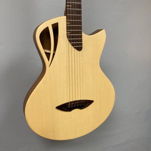 Murray Kuun Coupe Natural Acoustic Guitar hanging on wall, showcasing detailed close-up of strings and wood craftsmanship, highlighting its musical elegance.