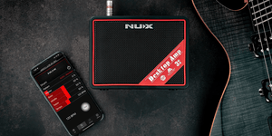 NUX Mighty Lite BT MKII Desktop Guitar Amp next to a phone displaying a music app, highlighting its versatile guitar and bass effects.