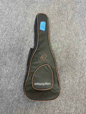 An Ortega RUSWB-UB Uke Bass Stonewashed gig bag by Ortega rests on a gray carpet .