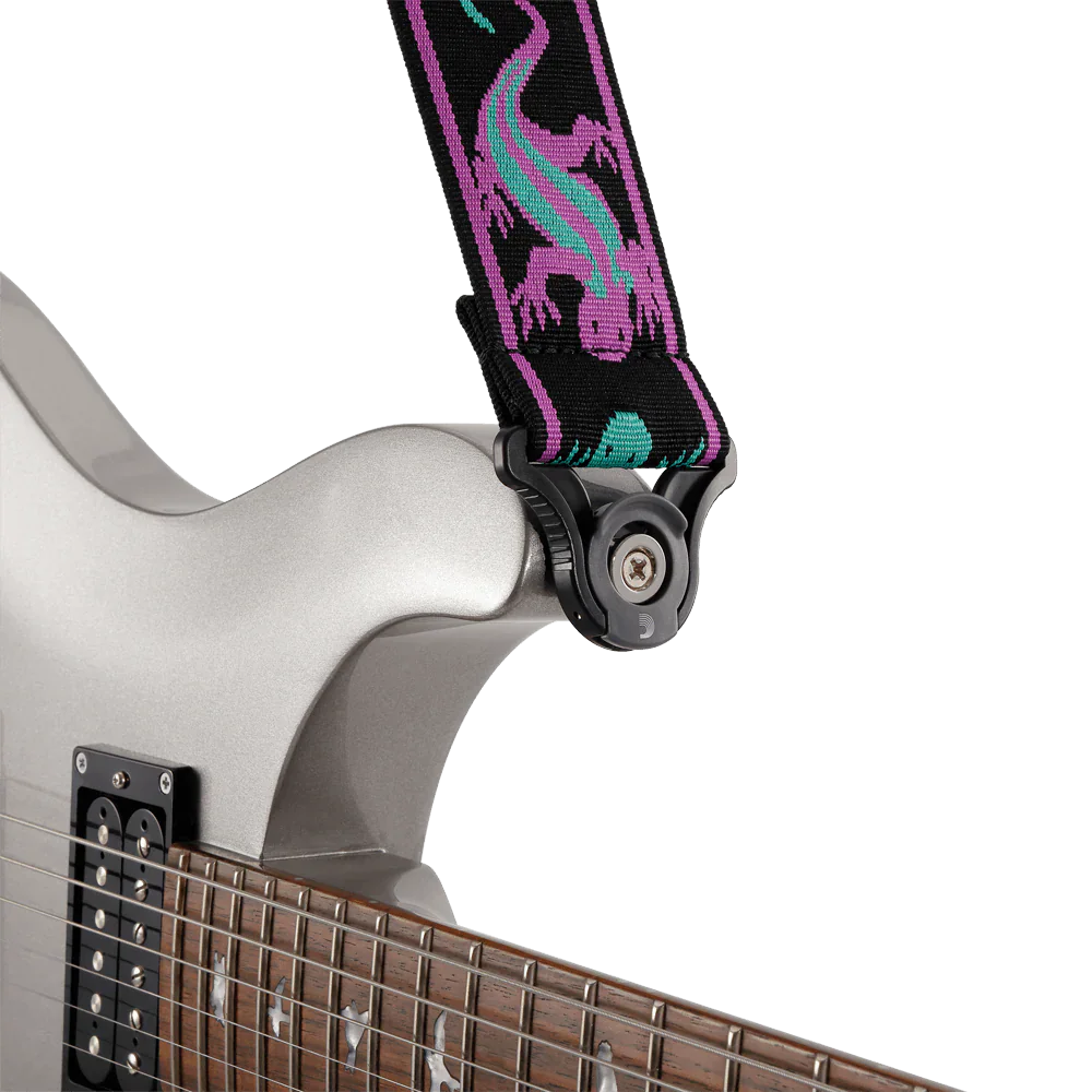 Close-up of a silver electric guitar fitted with a Planet Waves Auto Lock Guitar Strap in Green / Purple Lizards, securely attached to the instrument.