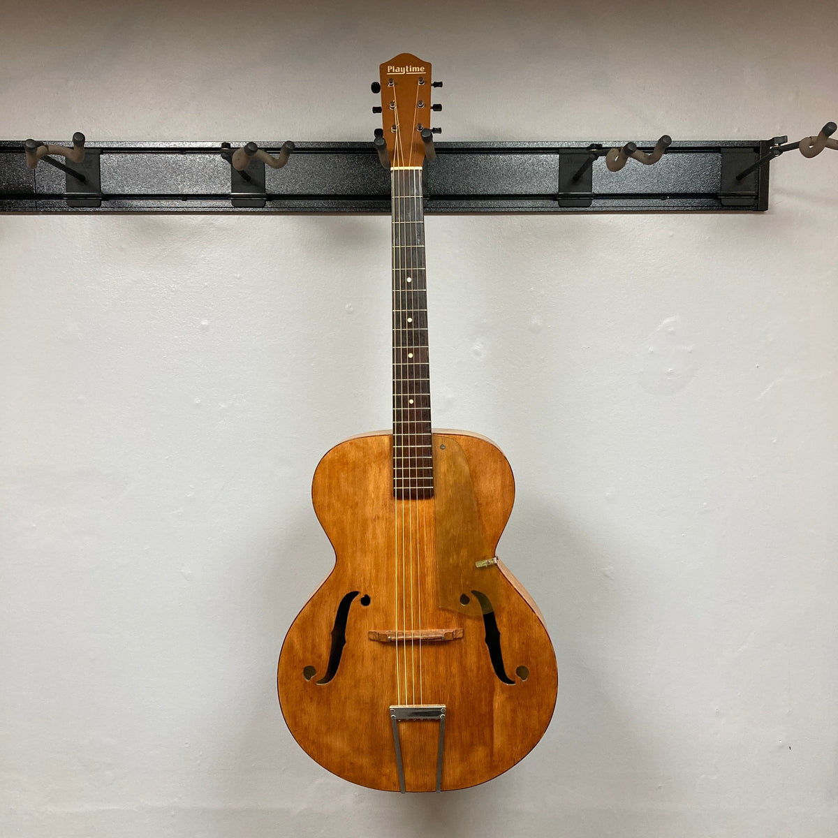 Playtime by Harmony Vintage Archtop Guitar 1940&#39;s hanging on a hook, showcasing its classic design and well-preserved condition, ideal for musicians and collectors.